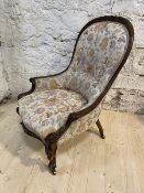 A Victorian rosewood nursing chair with later floral upholstery, with moulded top rail arms and