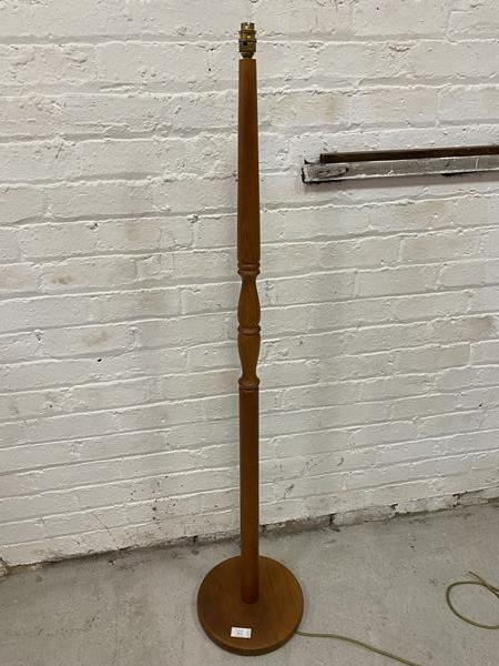 A teak standard lamp with turned stem on circular base, measures 143cm to top of lamp holder