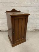 An Edwardian walnut bedside cabinet with moulded gallery back the panelled door before single