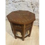 A middle eastern octagonal occasional table with brass inlay to top, on pierced folding base,