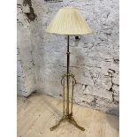 A brass standard lamp with adjustable stem, having three supports with C scrolls, on tripod support,