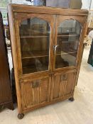 A 1930's / 40's oak bookcase over cabinet the caddy top over two glazed doors before two shelves