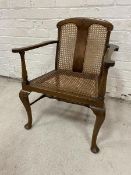 An early 20thc open armchair with caned back and seats, scrolled arms on turned supports on cabriole