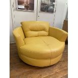 An oversized contemporary circular swivel lounge chair upholstered in yellow leather, measures