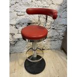 A retro swivel bar stool with red vinyl curved back and circular seat,