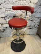 A retro swivel bar stool with red vinyl curved back and circular seat,