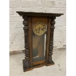 A Vienna regulator style clock dial with roman numerals behind door with glass panel flanked by