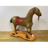 A vintage child's toy horse with horse hair exterior and leather saddle on wooden base with four