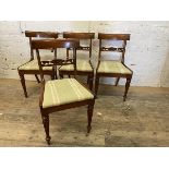 A set of four Regency style mahogany dining chairs with floral carved back rails on front tapering