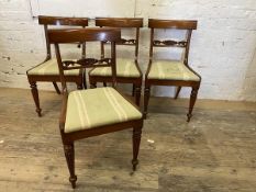 A set of four Regency style mahogany dining chairs with floral carved back rails on front tapering