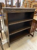 A 1920's / 30's oak open bookcase, the rectangular top with moulded edge over carved frieze with two