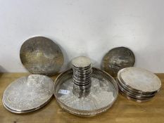 A group of coasters with polished metal tops having C scroll and leaf decoration, in three graduated