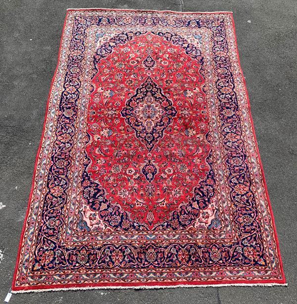 A Persian Kashan design handknotted rug, red field with blue medallions and spandrels, trailing