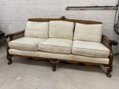 A Regency inspired three seater sofa with shell surmount over caned back and sides, scrolled arms