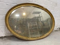 An Edwardian wall mirror, the bevel oval glass within gilt frame,