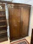 A 19thc mahogany bow front wardrobe with dentil cornice over panelled doors before single shelf