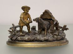 A 19th century parcel-gilt bronze novelty inkstand, modelled with a boy feeding a dog emerging