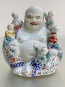 A Chinese famille rose porcelain group of a laughing Buddha with five children, the unglazed base
