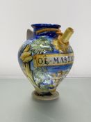 An Italian maiolica wet drug jar, 20th century, painted with a putto in a landscape with churches,