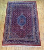 A Persian Heriz design rug, hand knotted, the red field with lozenge medallion, multiple lotus