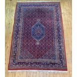 A Persian Heriz design rug, hand knotted, the red field with lozenge medallion, multiple lotus