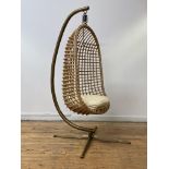 A hanging basketwork chair, circa 1970's, the openwork seat of egg form with associated cushion