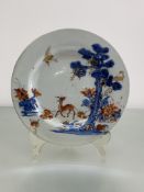 A Chinese porcelain plate decorated in an Imari palette with a deer beside a pine tree, with a crane