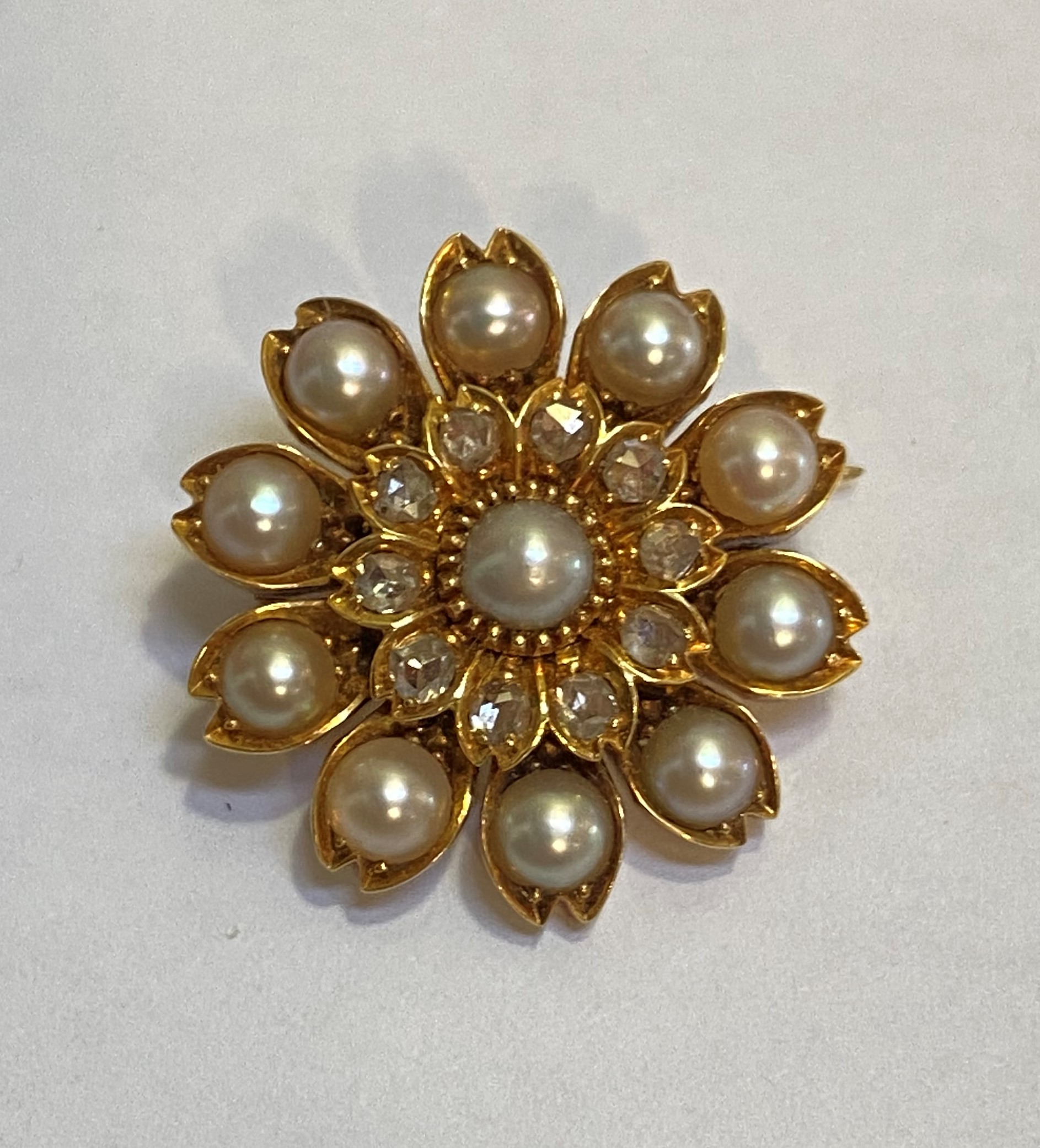 A seed pearl and diamond brooch, of flowerhead form, probably late 19th century, the central pearl