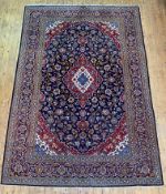A Persian Kashan rug, hand knotted, the deep blue field with blue red and ivory lozenge medallion,