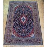 A Persian Kashan rug, hand knotted, the deep blue field with blue red and ivory lozenge medallion,