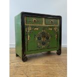 A Chinese green lacquered cabinet, two drawers over two cupboards opening to a shelf behind, the