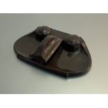 A patinated bronze desk standish, early 20th century, possibly German, of shaped oval form, with