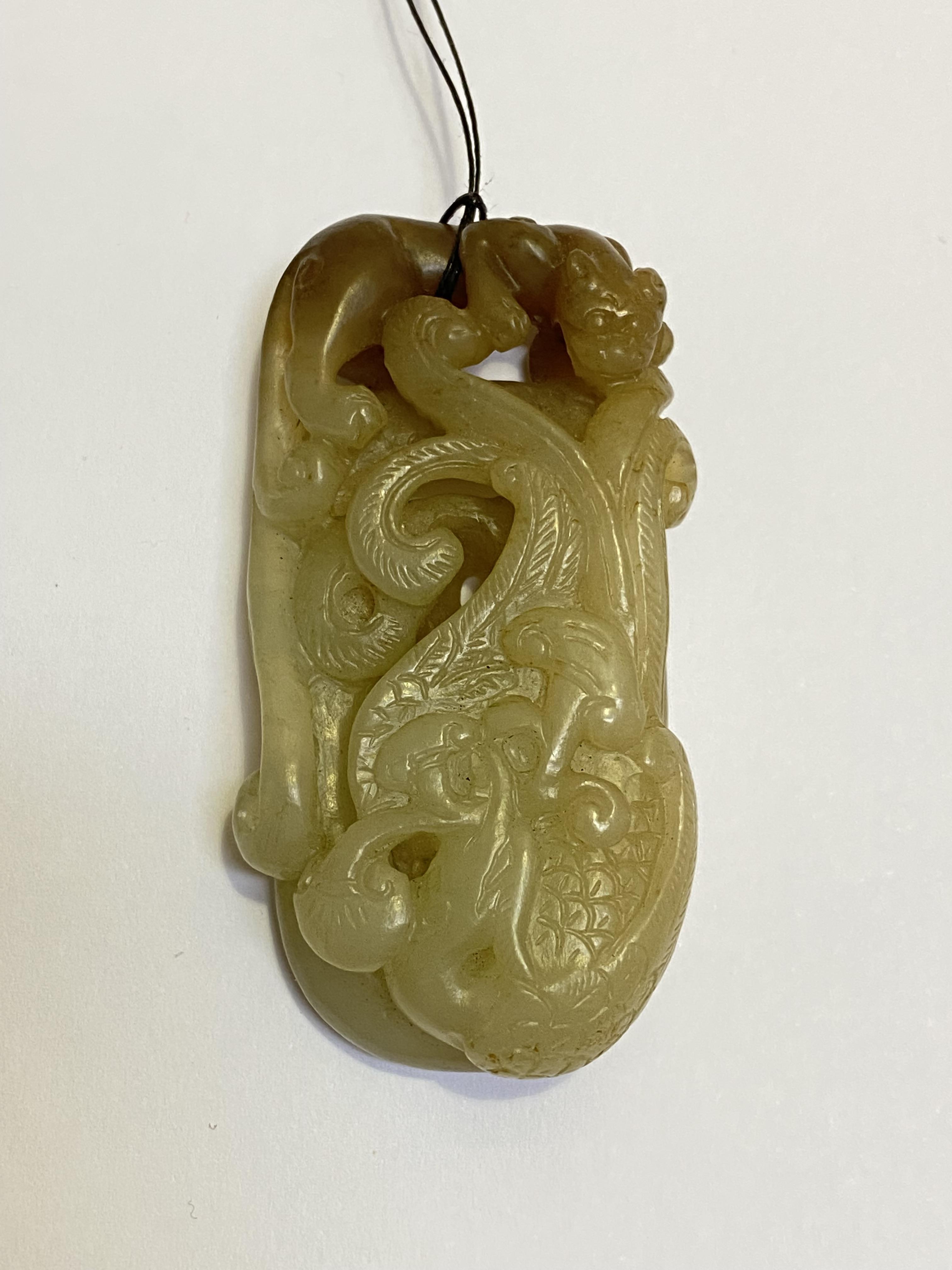 A Chinese carved celadon jade pendant, modelled with chilong, with brown inclusions. Length 6cm