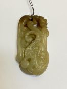 A Chinese carved celadon jade pendant, modelled with chilong, with brown inclusions. Length 6cm