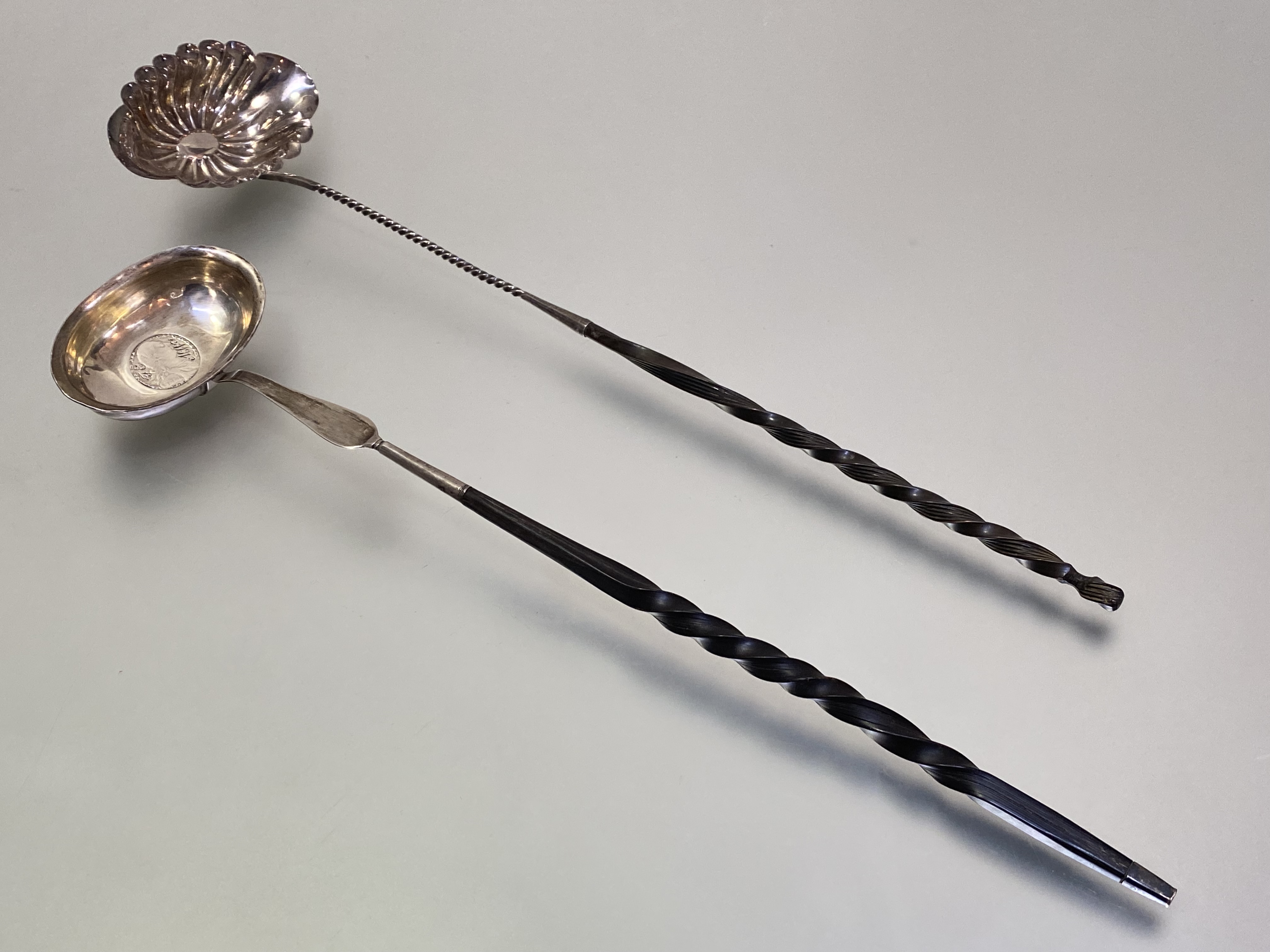 A George III white metal toddy ladle, c. 1800, with coin-inset oval bowl on a balleen twist