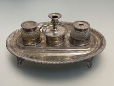 An early 19th century silver desk standish, the oval stand with gadrooned edge and raised on