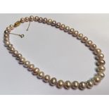 A graduated single strand cultured pearl necklace, of pink lustre, round and bouton shapes, on a 9ct