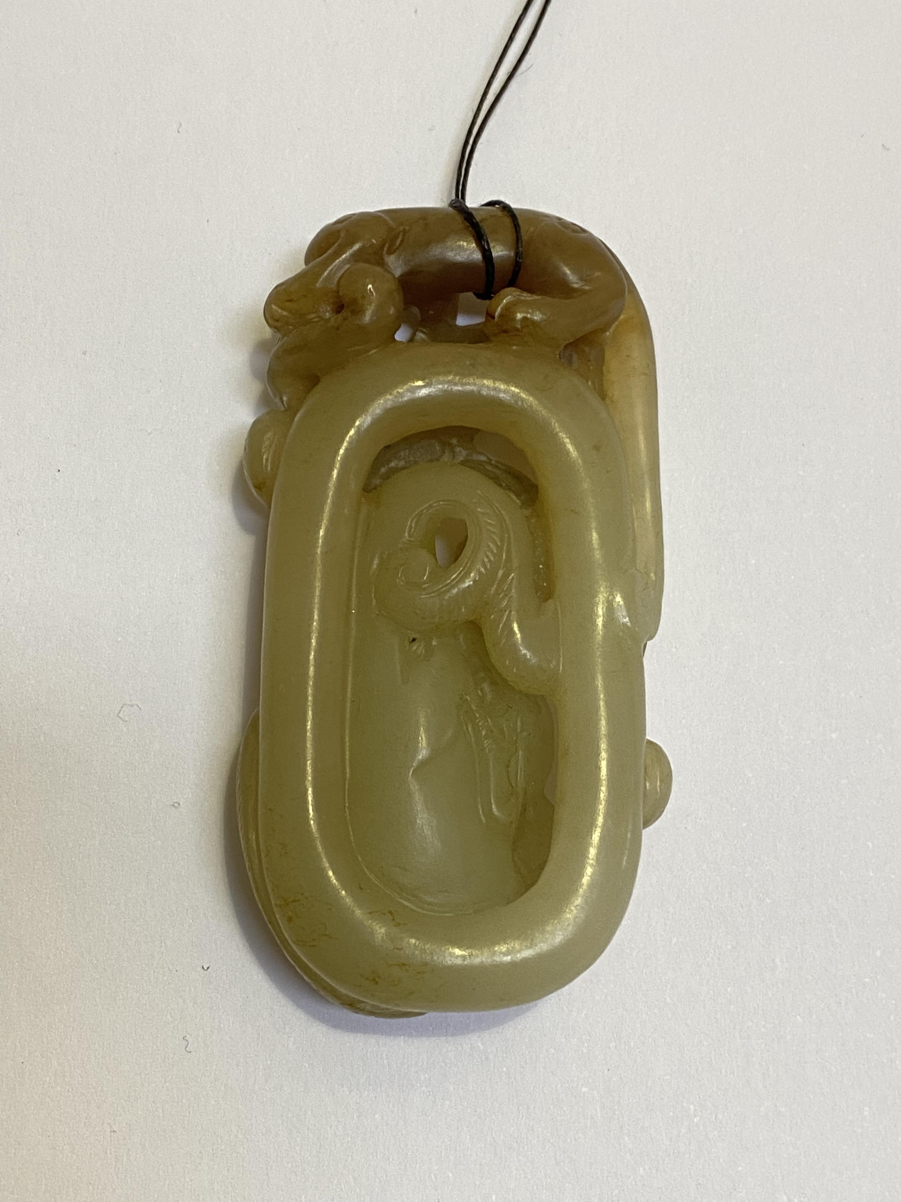 A Chinese carved celadon jade pendant, modelled with chilong, with brown inclusions. Length 6cm - Image 2 of 2