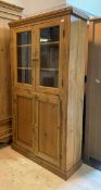 A reclaimed pine kitchen larder cabinet, with two glazed doors enclosing two shelves, over two doors