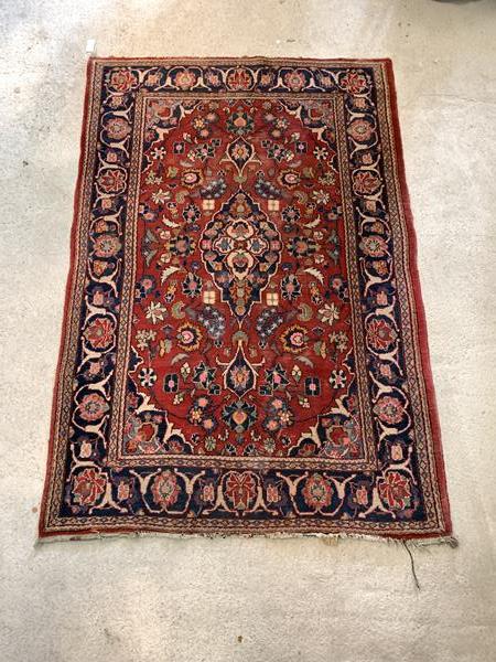 An old Persian Tabriz design rug, hand knotted, the red field having blue medallion and interlaced