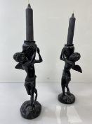 A pair of cast metal winged young boys carrying jars (each: 22cm to top of jar)