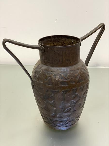 An Eastern copper hammered twin cast iron handled vase with centre panel with Arabic script enclosed