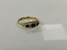 An 18ct gold gem set ring with three sapphires separated by pairs of chip diamonds, size O, weighs