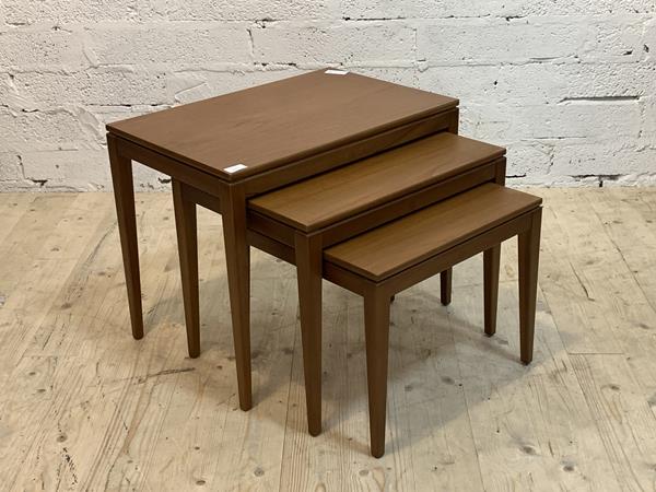 A mid century teak nest of three tables, raised on square tapered supports, H49cm, W60cm, D40cm