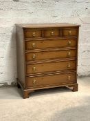 A Georgian style cross banded yew wood chest of drawers, late 20th century, with three short drawers