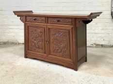 A Chinese hardwood alter table cabinet, the panelled top with scroll ends over two drawers and