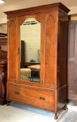 An Edwardian mahogany wardrobe, the mirrored door enclosing rail, over drawer to base, raised on