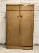 An Art Deco period birds eye maple wardrobe, the caddy top over two doors enclosing an interior