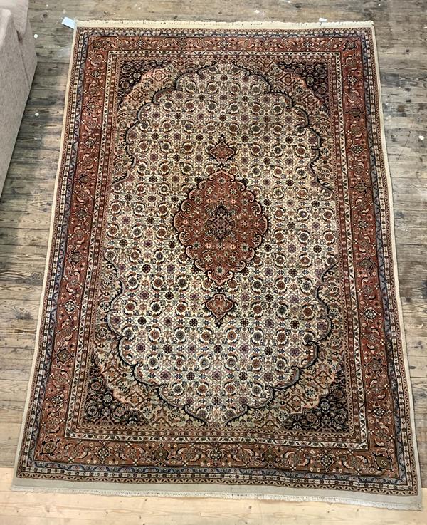 A Persian Tabriz design carpet, ivory field with medallion and multiple flower heads and