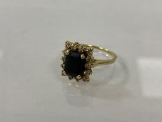 A 14k gold cluster ring with fourteen chip diamonds surrounding dark blue stone, size O/P, weighs